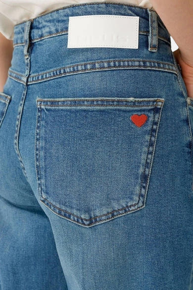 Jean large en denim bleu moyen d'OPUS, avec une poche arrière agrémentée d'un cœur rouge.
