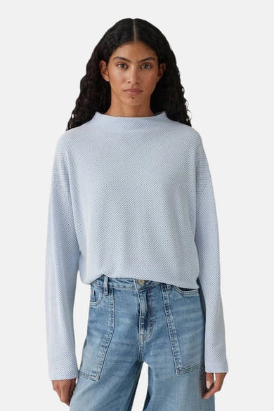 Top uni manches longues bleu clair par OPUS, avec une texture gaufrée, porté avec un jean taille haute.
