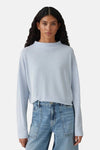 Top uni manches longues bleu clair par OPUS, avec une texture gaufrée, porté avec un jean taille haute.
