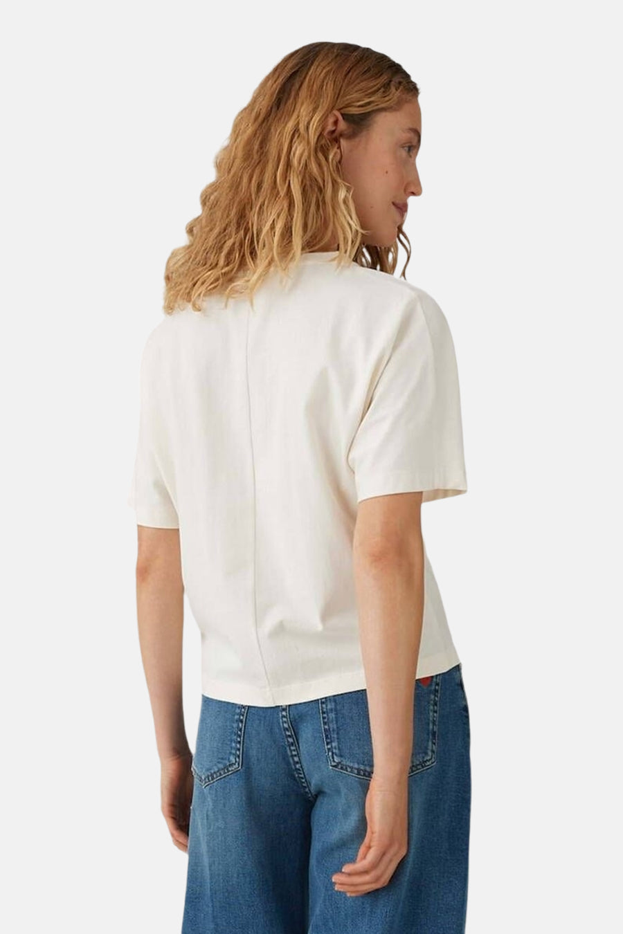 Top uni manches courtes beige d'OPUS, avec une couture verticale au dos, porté avec un jean bleu taille haute.