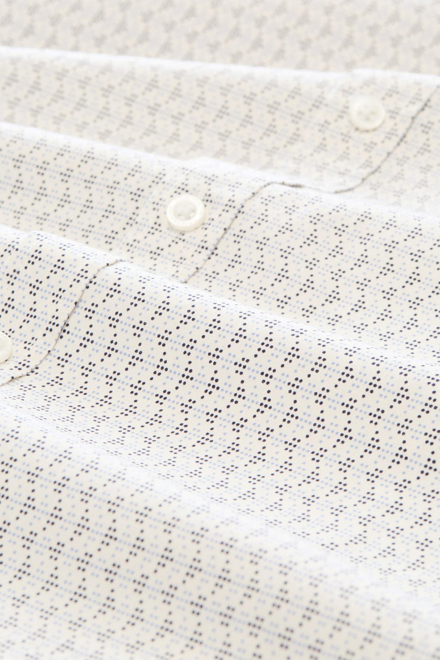 White long-sleeve shirt with subtle blue and black dot pattern, close-up view of collar and buttons