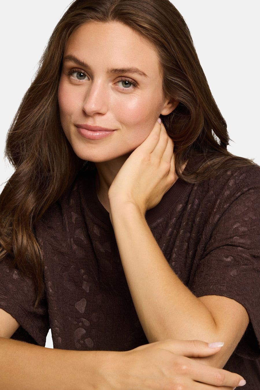 Brown short-sleeve T-shirt with textured abstract pattern, worn by model in lifestyle close-up view