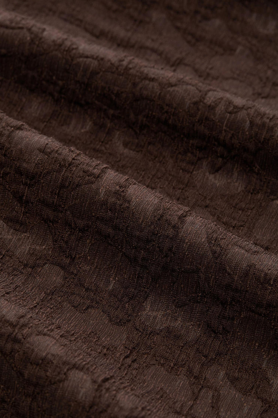 Brown short-sleeve t-shirt with textured fabric, close-up view showing intricate weave pattern and soft folds
