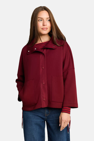 Burgundy cardigan with button front and side pockets, featuring striped cuffs and collar details, worn over a striped top with blue jeans, front view.