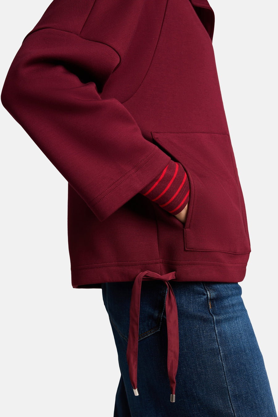 Burgundy cardigan with striped cuffs and drawstring hem, side view, worn with blue jeans
