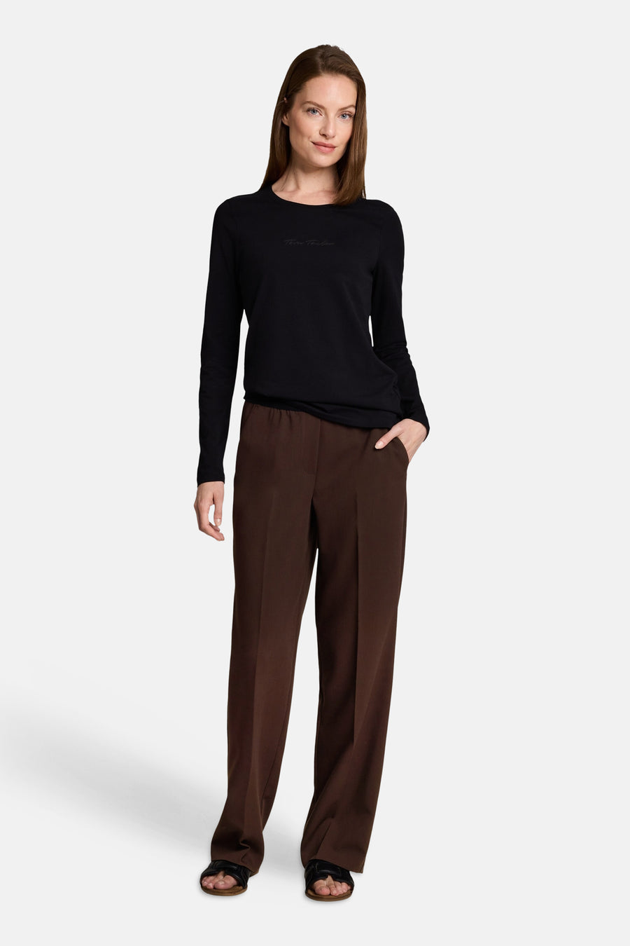 Pantalon brun élastique pour femme par Tom Tailor, coupe large, porté avec un haut noir et sandales plates, vue de face.