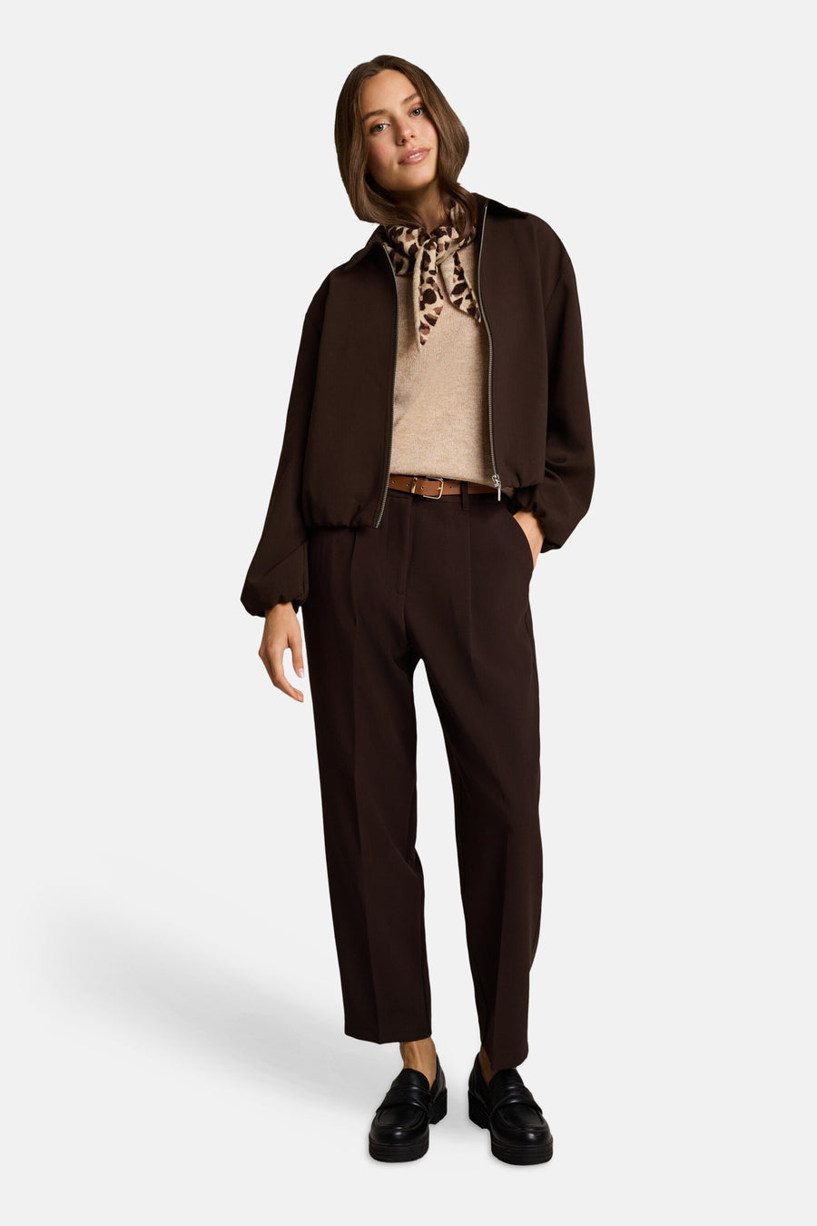 Veste bomber marron pour femme par Tom Tailor, vue de face, avec col montant et fermeture éclair, portée avec un pull beige et un foulard léopard.