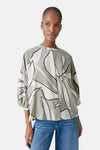 Chemisier 3/4 multicolore par OPUS, à motif abstrait vert et blanc, porté avec un jean taille haute.

