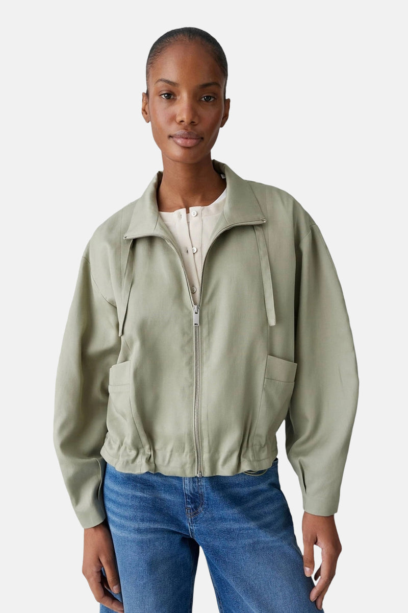 Veste courte verte par OPUS, à manches longues, avec fermeture éclair et poches, portée avec un jean bleu.