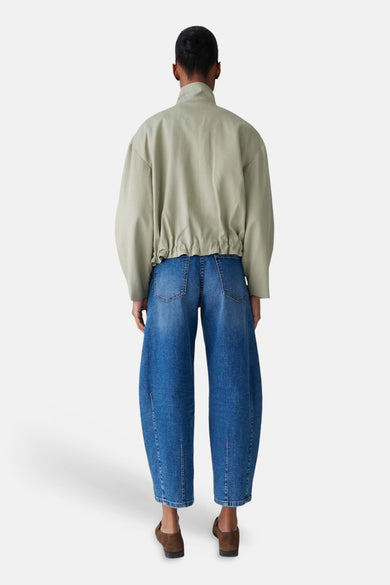 Veste courte vert clair de OPUS, avec une taille élastiquée, portée avec un jean ample bleu.