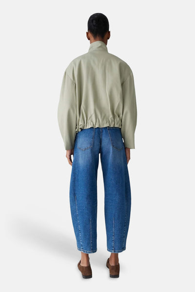 Veste courte vert clair de OPUS, avec une taille élastiquée, portée avec un jean ample bleu.