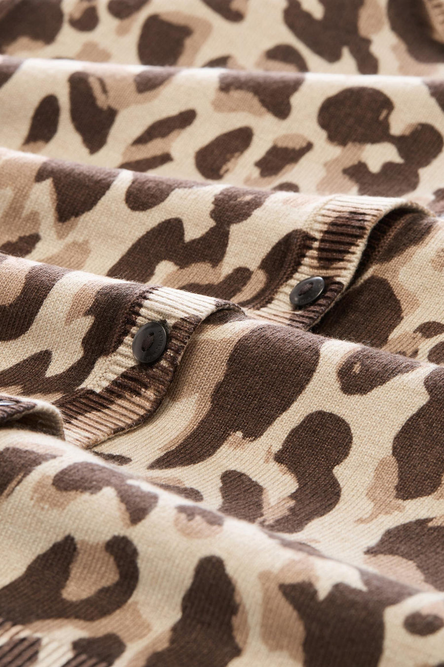 Multicolored camouflage knit cardigan with ribbed placket and black buttons, close-up view