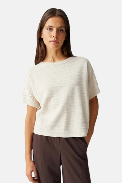 Top uni à manches courtes vert de OPUS, porté avec un pantalon marron.
