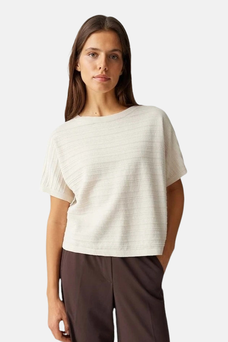 Top uni à manches courtes vert de OPUS, porté avec un pantalon marron.
