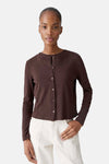 Cardigan brun de OPUS, boutonné sur le devant, porté avec un pantalon écru.
