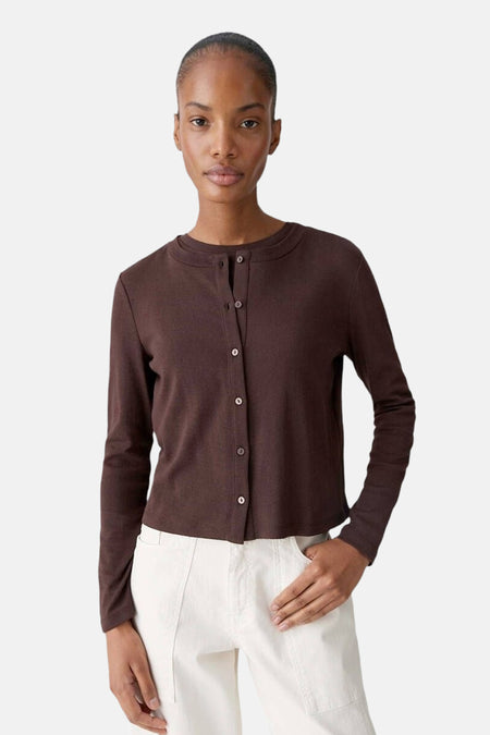 Cardigan brun de OPUS, boutonné sur le devant, porté avec un pantalon écru.
