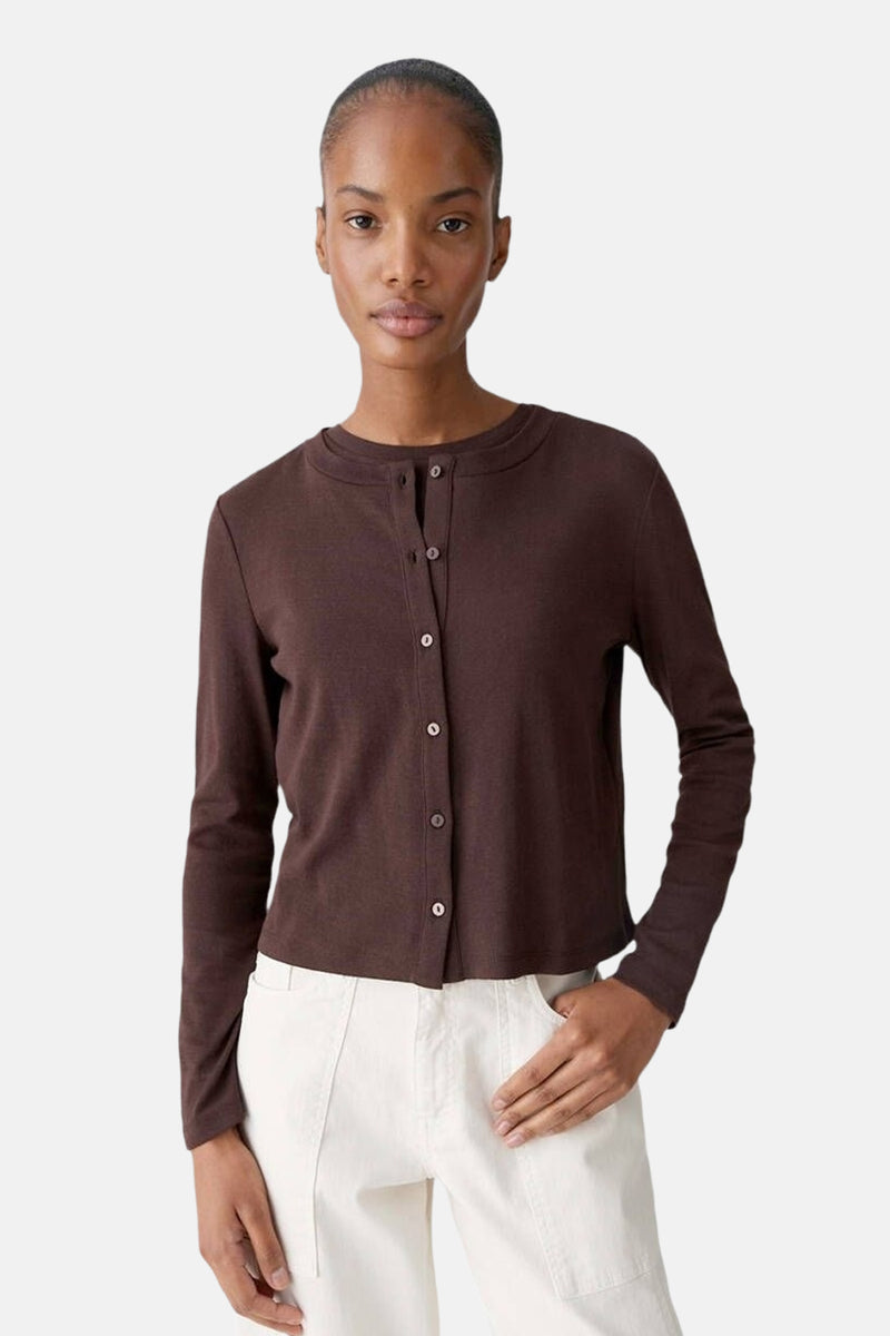 Cardigan brun de OPUS, boutonné sur le devant, porté avec un pantalon écru.
