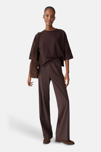 T-shirt brun uni à manches courtes par OPUS, porté avec un pantalon assorti et un sac à bandoulière en daim.
