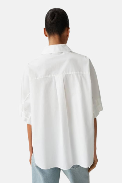 Chemise blanche de OPUS à manches courtes, coupe ample, vue de dos avec pli creux et ourlet incurvé, portée avec un jean clair.