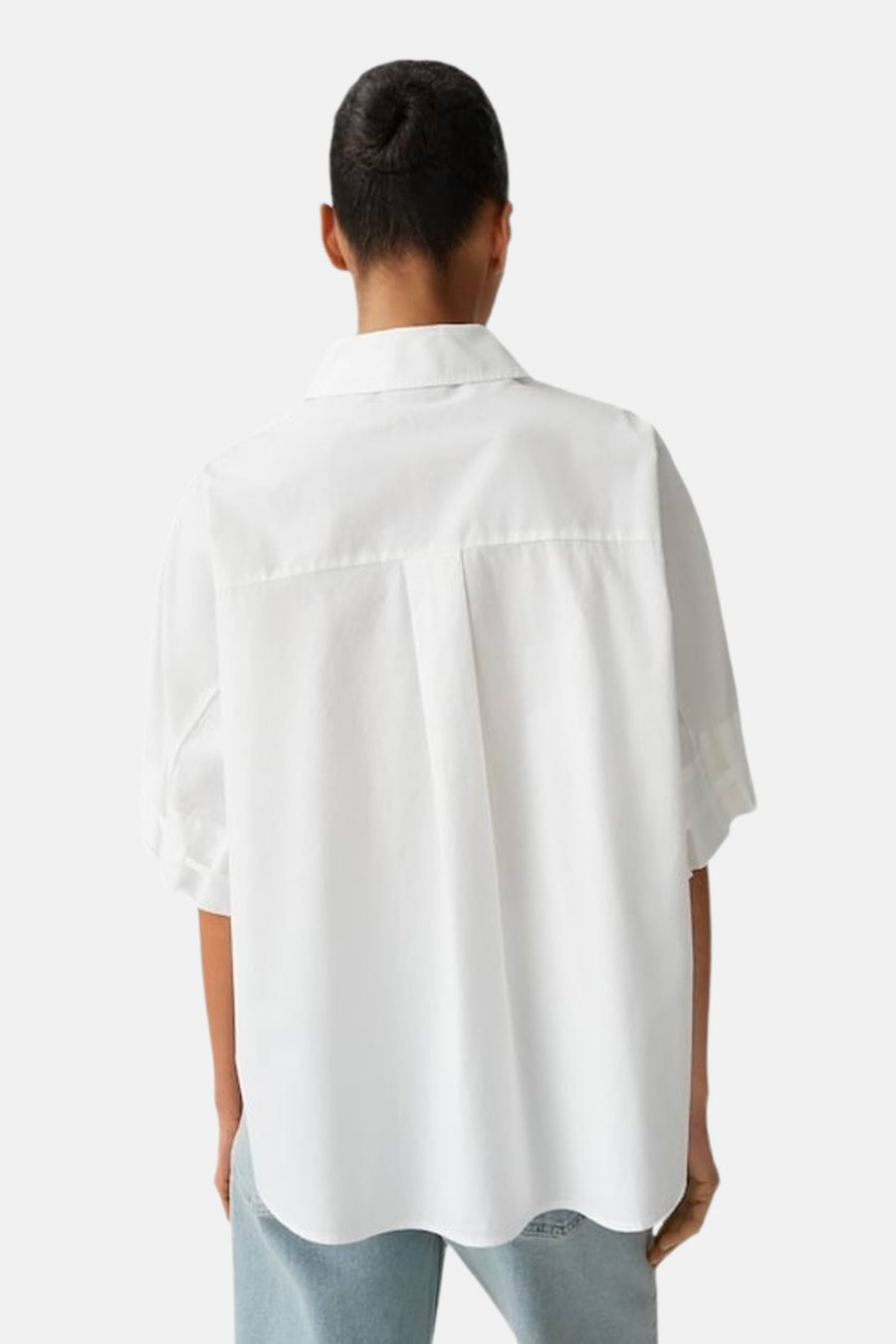 Chemise blanche de OPUS à manches courtes, coupe ample, vue de dos avec pli creux et ourlet incurvé, portée avec un jean clair.