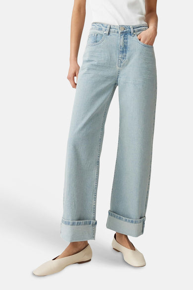 Jeans larges bleu clair en denim de la marque OPUS, avec taille haute et ourlets retroussés, portés avec des ballerines claires.