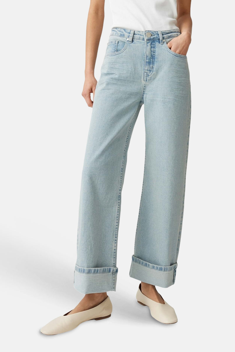 Jeans larges bleu clair en denim de la marque OPUS, avec taille haute et ourlets retroussés, portés avec des ballerines claires.