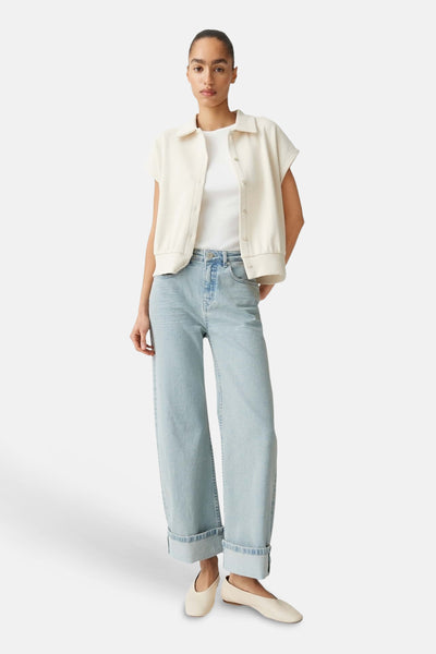 Jeans larges bleu clair de OPUS avec des ourlets retroussés, portés avec une veste courte écrue et des chaussures plates.