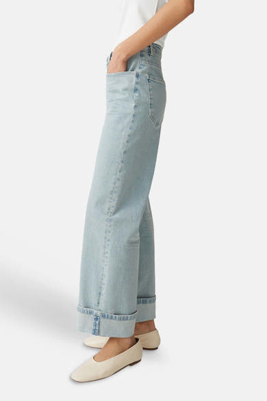 Jeans larges bleu clair en denim de OPUS avec revers aux chevilles, portés avec des chaussures plates claires.