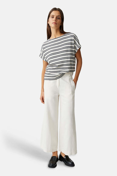 T-shirt à rayures noires et blanches à manches courtes et col bateau d'OPUS, porté avec un pantalon blanc et des mocassins noirs.