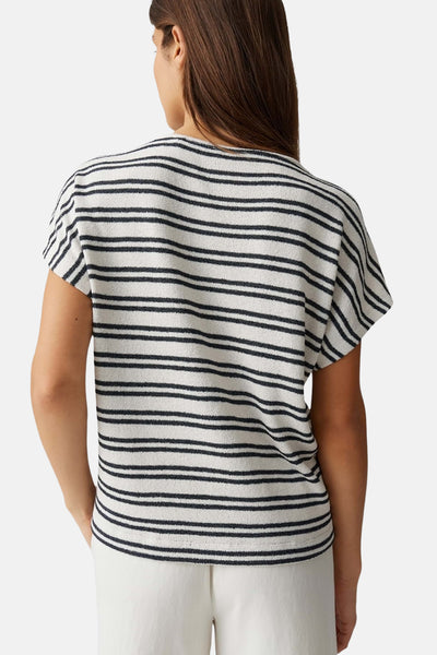 T-shirt rayé blanc et noir de OPUS, à manches courtes, en tissu texturé, vu de dos avec un pantalon blanc.