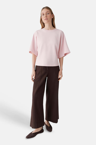 T-shirt rose à manches courtes amples de OPUS, col rond, porté avec un pantalon marron large et des chaussures plates.