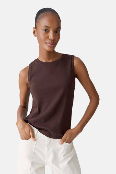 Top sans manches brun, par OPUS, porté avec un pantalon blanc à poches, devant un fond neutre.