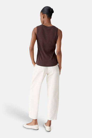 Top (sans manches) brun d'OPUS, porté avec un pantalon blanc taille haute et des ballerines blanches, vue de dos.