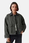 Oversized green parka with front zipper and flap pockets, worn over a white top and dark jeans, front view.