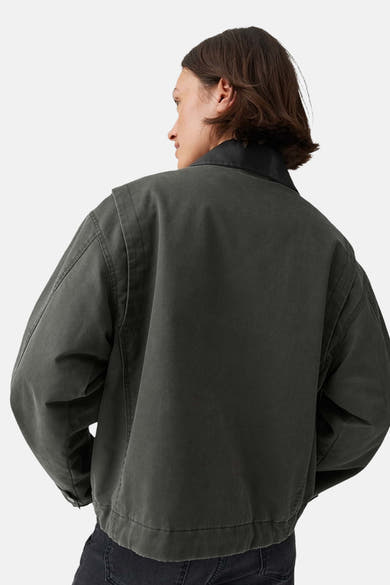 Oversized olive green parka with black ribbed collar, back view, worn with dark jeans