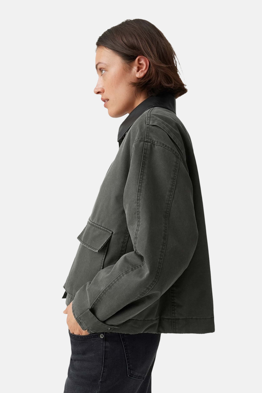 Olive green parka with black collar and side pockets, side view, worn with dark jeans