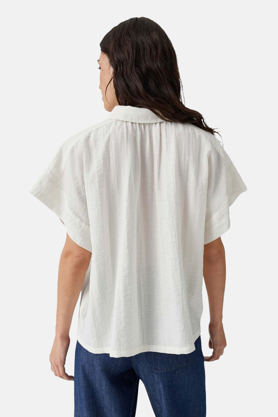 White sleeveless blouse with relaxed fit and textured fabric, back view, worn with blue jeans