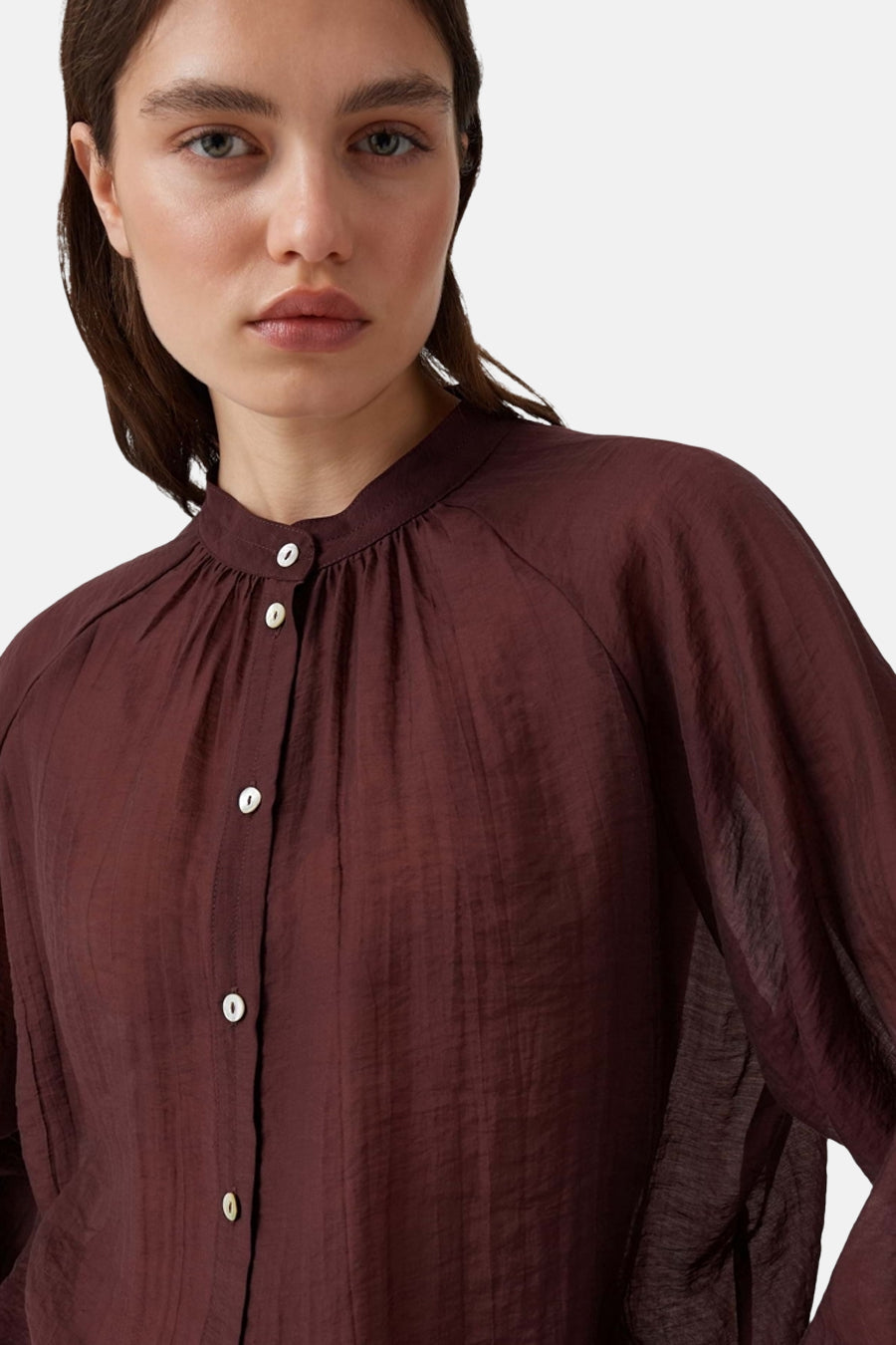 Bordeaux long-sleeve blouse with gathered neckline and white buttons, textured fabric, front view