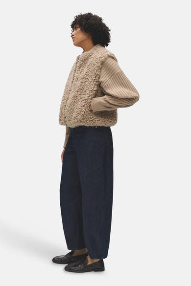 Veste sans manches beige OPUS en matière bouclée, portée de profil sur un pull côtelé.