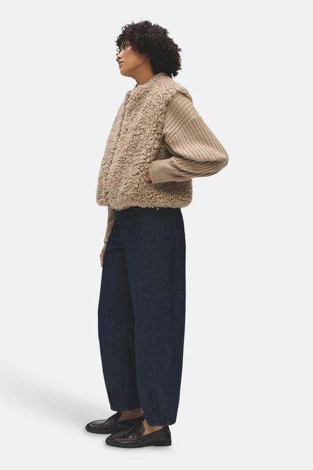 Veste sans manches beige OPUS en matière bouclée, portée de profil sur un pull côtelé.