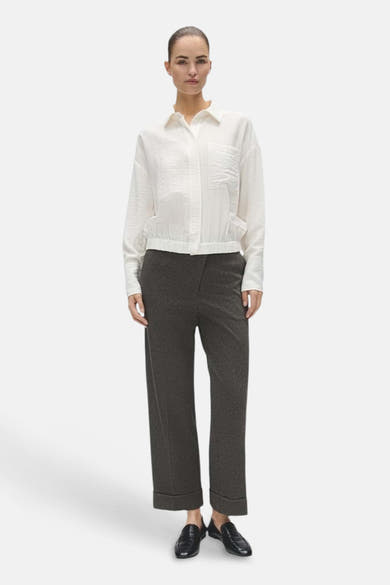 Blouse écrue OPUS à manches longues, col chemise et poches, portée avec un pantalon sombre.