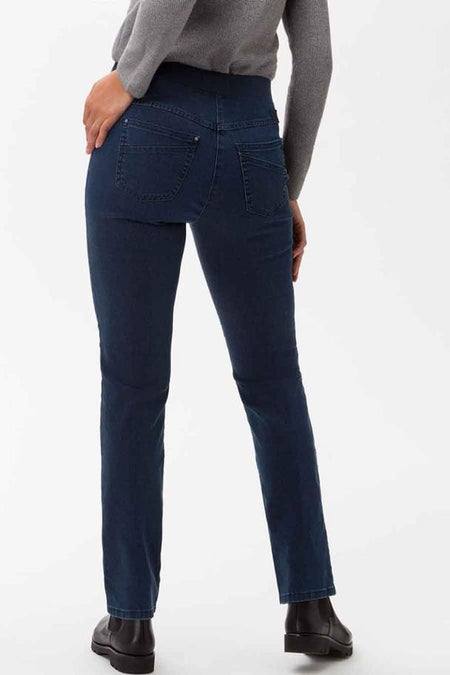 Jean bleu marine de RAPHAELA, avec poches arrière, porté avec un pull gris et des bottines noires.