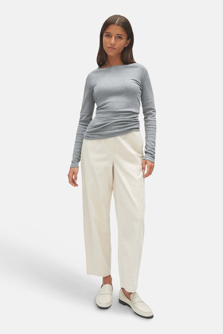 Top gris uni à manches longues de OPUS, porté avec un pantalon blanc et des mocassins, vue de face.