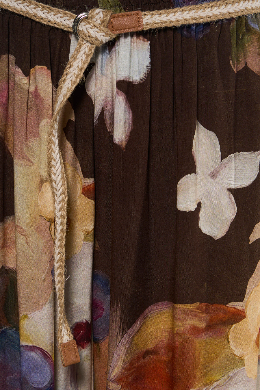 Brown floral print women's elastic waist pants with woven rope tie and leather accents, close-up front view