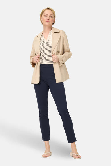 Pantalon de costume bleu de RAPHAELA, porté avec un haut rayé et un trench beige.