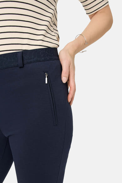 Pantalon de costume bleu by RAPHAELA, avec ceinture décorative et poche zippée, porté avec un haut rayé.
