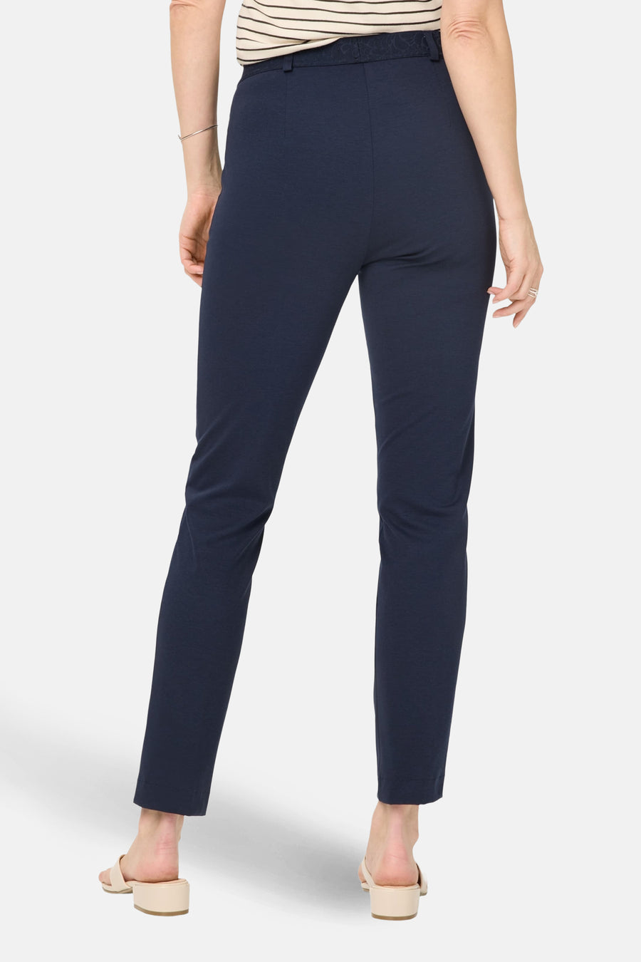 Pantalon de costume bleu de RAPHAELA, coupe droite, porté avec un haut rayé et des mules beiges, vue de dos.
