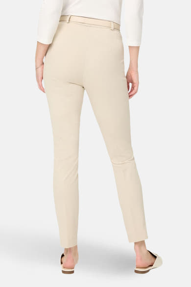 Pantalon de costume écru de RAPHAELA, coupe ajustée, avec ceinture ton sur ton et chaussures plates.

