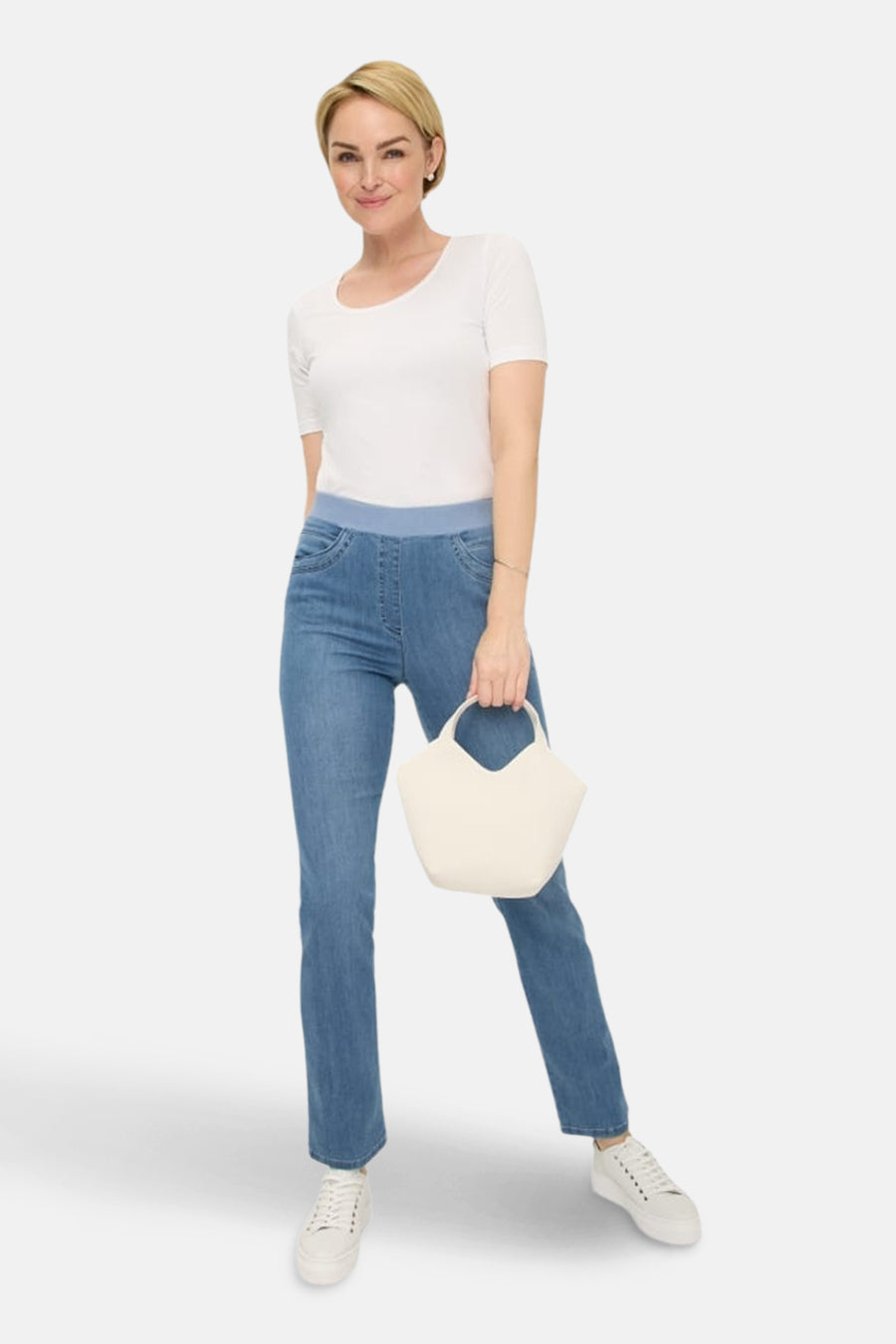 Slim jeans in lichtblauw denim van RAPHAELA, gedragen met een wit T-shirt en witte sneakers.