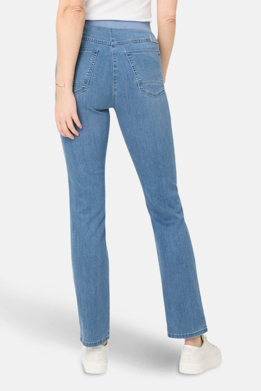 Slim jeans in lichtblauw denim van RAPHAELA, met achterzakken, gedragen met witte schoenen.